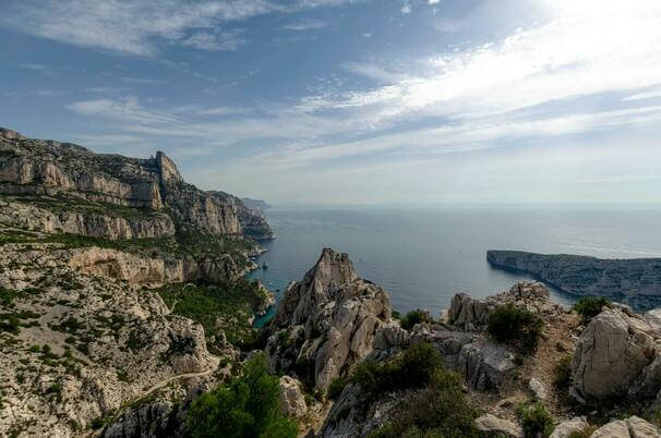 Photo des calanques de la mediterranée, mêlant roche, végétation et mer sur un grand ciel bleu.