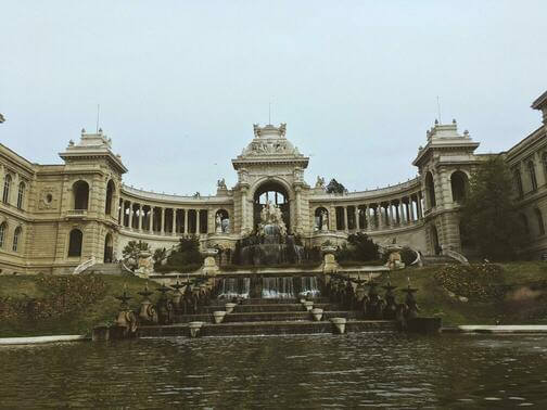 Photo du parc Longchamp : une imposante fontaine au premier plan, surplombée par des statues et ceinte par un bâtiment circulaire.