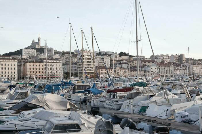 Vue sur le port de Marseille et ses nombreux bâteaux, avec la ville et Notre-Dame-de-la-Garde en arrière plan0